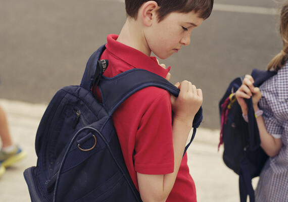 Two children wearing school uniforms and school bags walking to school.