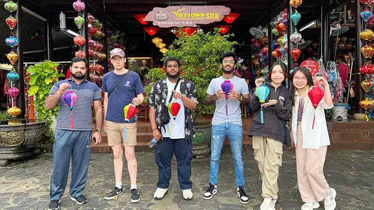 Student Taha and friends outside a silk shop holding lanterns