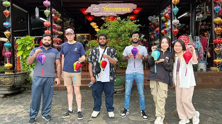 Student Taha and friends outside a silk shop holding lanterns