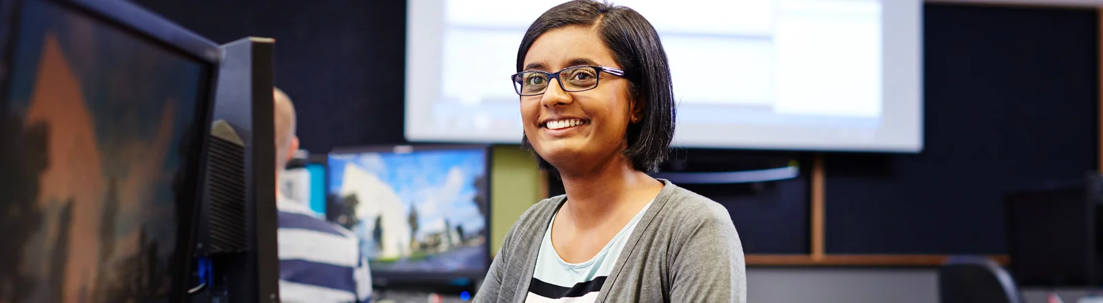 An IT student smiles while they work during class