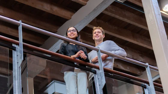 Two students look out from a mezzanine.