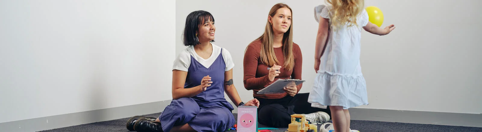 Two Deakin master of child play therapy students interact with a small child.