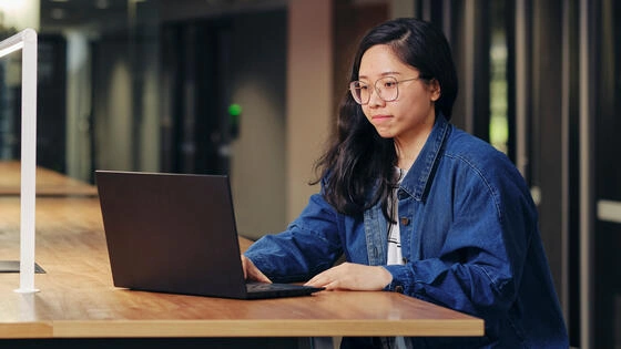 Deakin master of information technology management student sits on campus and studies on computer.