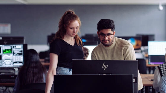 Two Deakin master of technology and innovation leadership students work on a computer together on campus.