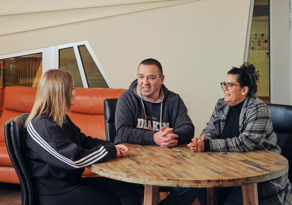 Three Deakin students sit at a table in the NIKERI Institute talking.