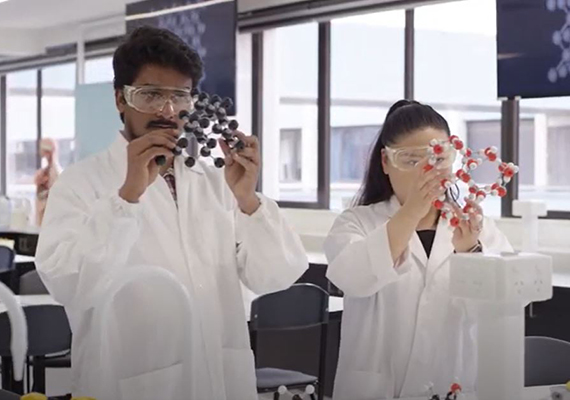 two Deakin conservation students stand in a lab looking at an atom model