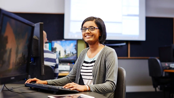 An IT student smiles while they work during class