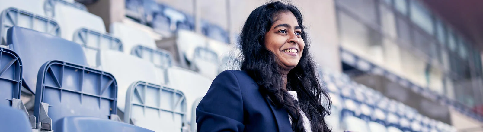 A Deakin master of business sport management sits in a stadium. 
