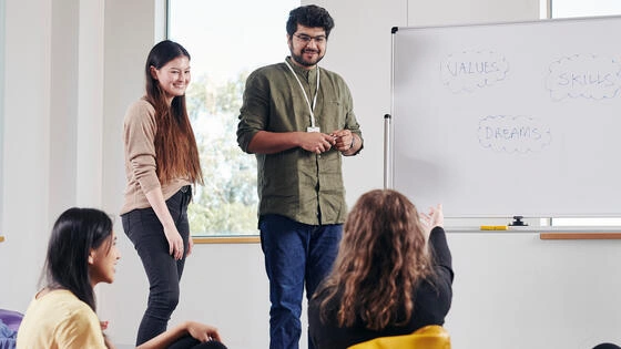 Two Deakin graduate diploma of health promotion student teachers teach in a classroom of four students.