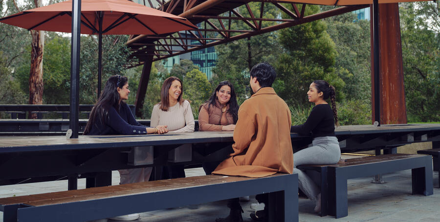 Group of Deakin students sit at a table at Deakin Melbourne Burwood Campus.