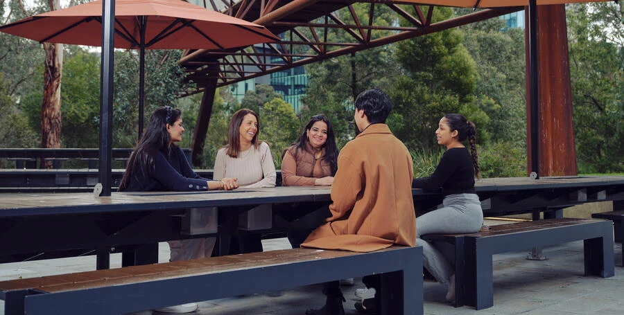 Group of Deakin students sit at a table at Deakin Melbourne Burwood Campus.