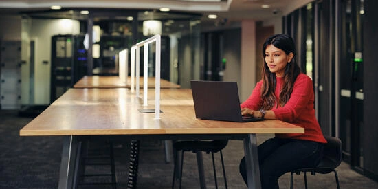 Deakin student sits at a desk looking at their laptop/