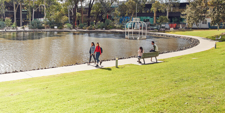 Deakin students walk around the Geelong Waurn Ponds pond.