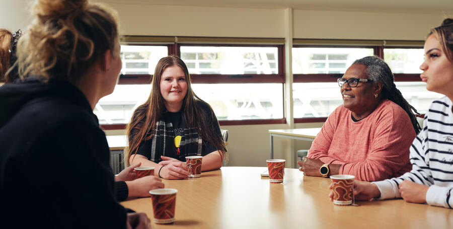 A group of students sit around a table chatting at the NIKERI Institute, Deakin University. 