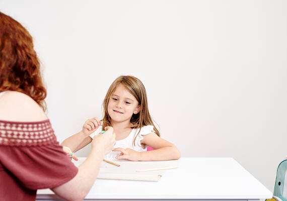A young child plays at a desk with a Deakin psychology student