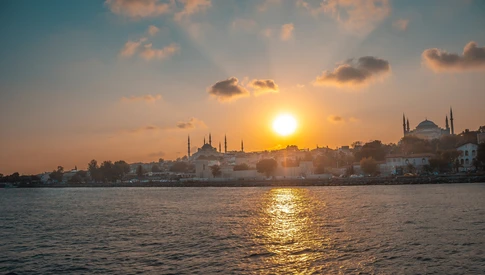 The skyline of Istanbul's historical peninsula, including prominent silhouettes of landmarks like the Hagia Sophia and Blue Mosque.The photo is taken from a boat on The Golden Horn, the primary inlet of the Bosphorus Strait.