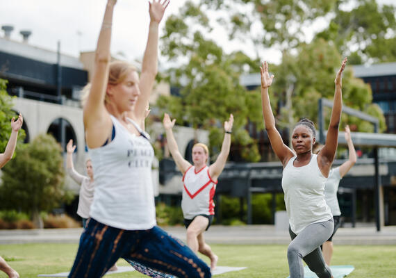 A group of people outside doing yoga.