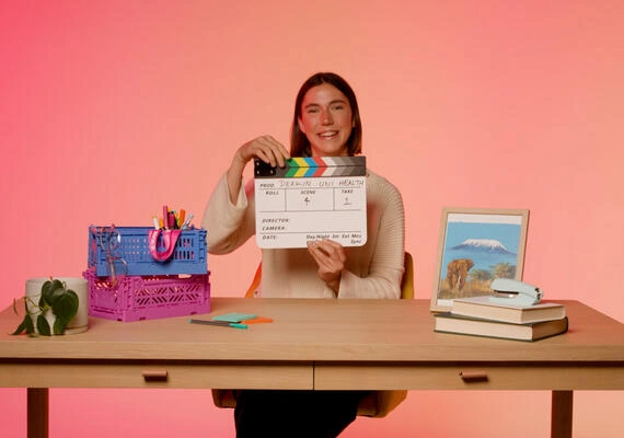 Bachelor of Nursing/Bachelor of Midwifery student sitting at a desk holding a clapboard. 