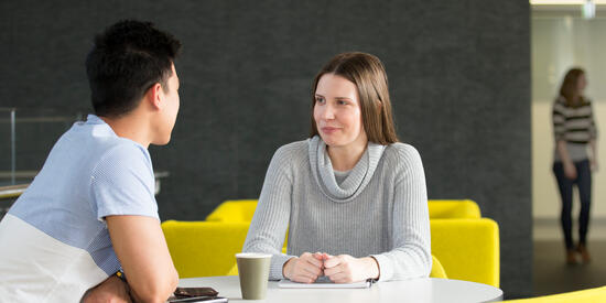 Two Deakin sociology students sit and chat with a coffee, Deakin Waurn Ponds Campus.