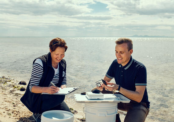 two marine biologists record data on the shore 