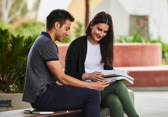 Two Deakin students on a bench reading