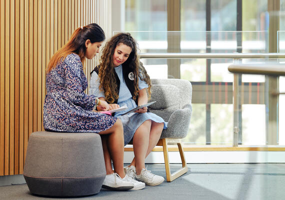 Two Deakin university students sits on a chair looking over a document together