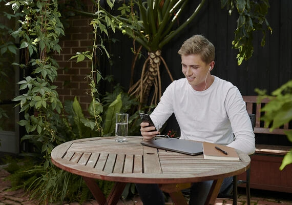 A Deakin student sits in a garden studying online