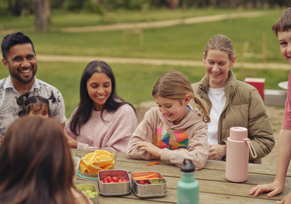 A family sitting together outdoors enjoying a healthy picnic.