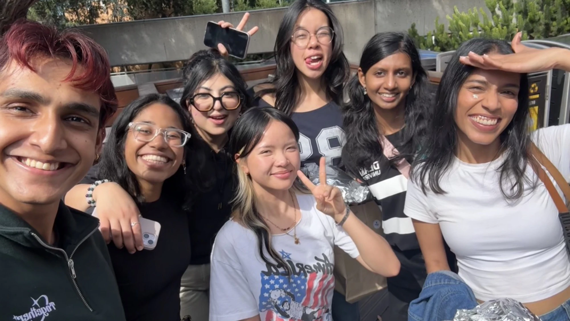 Gab and six other people smiling at the camera. They are outside, and the sun is on their faces.