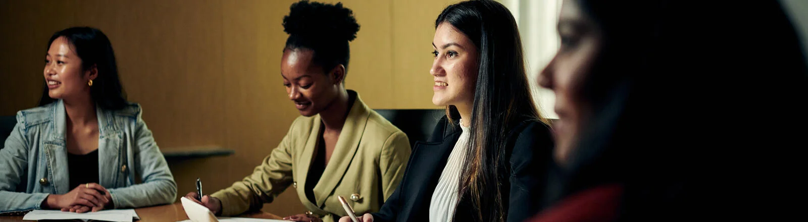 Three Deakin postgraduate recruitment students sit at a desk.