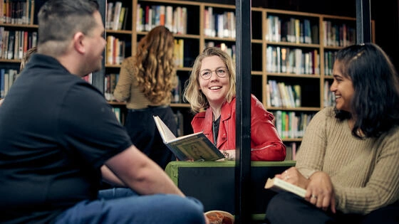 Three Deakin postgraduate writing and literature sit in the library. 