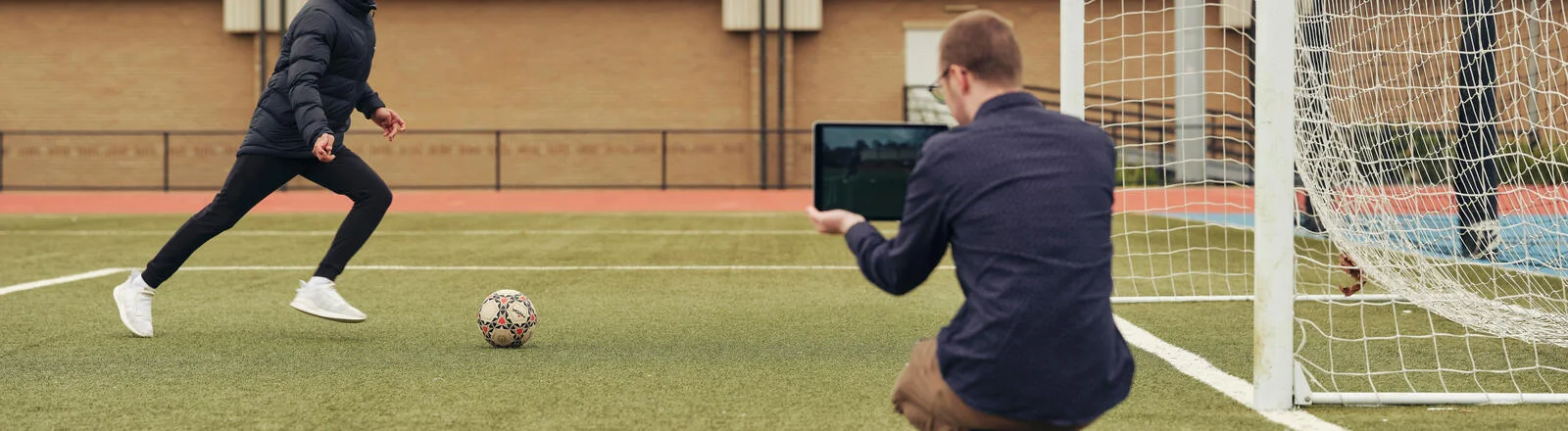 A Deakin bachelor of exercise student monitors a person kicking a soccer ball.