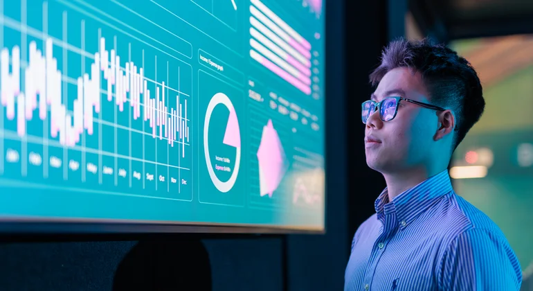 Business analytics student reviewing data on a big screen.