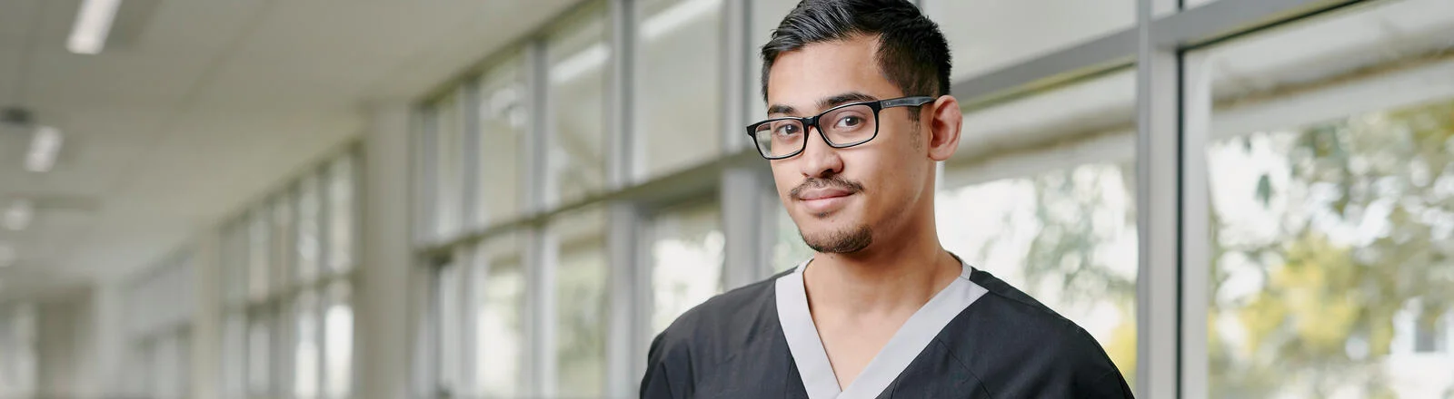 Deakin master of advanced nursing student stands in hallway looking at camera.