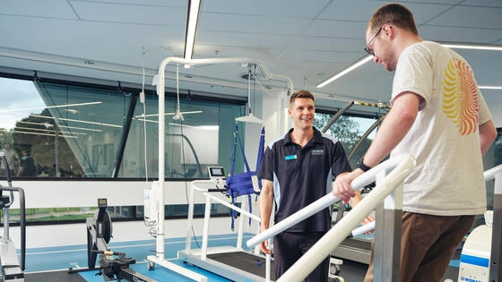 A Deakin master of clinical exercise physiology students helps a person in a rehab room.
