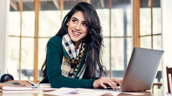 Deakin master of international relations student sits and smiles at desk on campus.