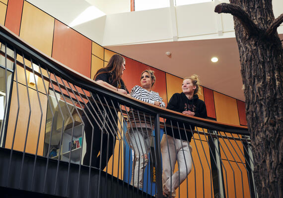 Two students talk at the NIKERI Institute. A colourful painting is in the background. 