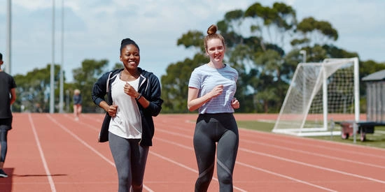 Two Deakin students running on a sport facility track at the Geelong Waurn Ponds Campus.
