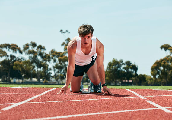 Close up of runner in crouched start position at the running track at Deakin.