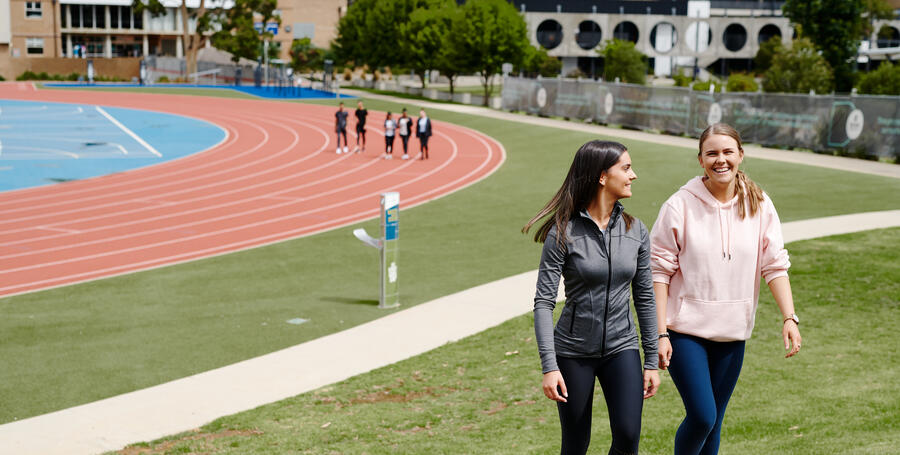 Two Deakin students walk together near the Waurn ponds campus running track