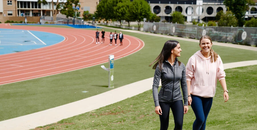 Two Deakin students walk together near the Waurn ponds campus running track