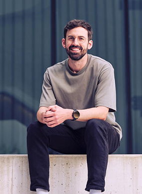 A Deakin law graduate sits on the wall at Melbourne Burwood Campus.