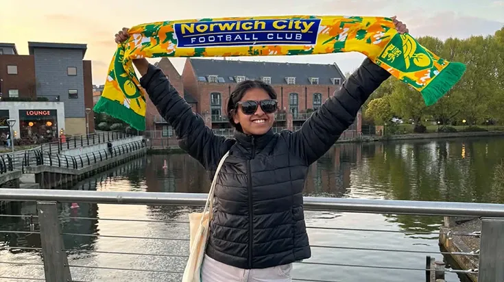 Sasha holding a scarf with the word "Norwich" over her head