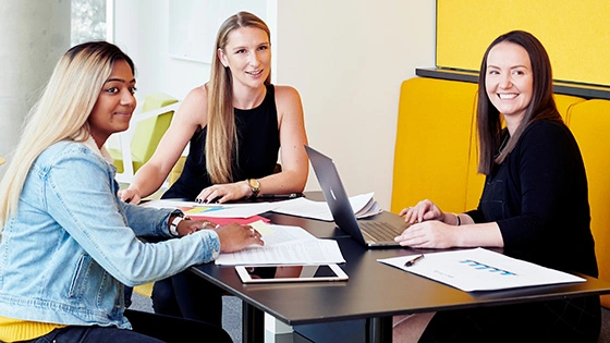 Three students discussing a topic on a table