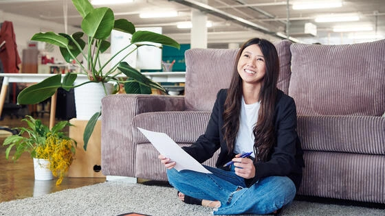 Deakin graduate diploma of communication student sitting on floor on campus smiling.