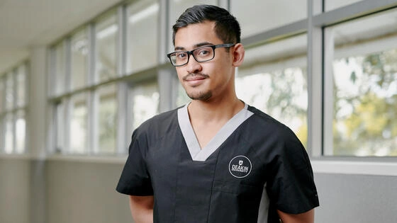 Deakin master of advanced nursing student stands in hallway looking at camera.