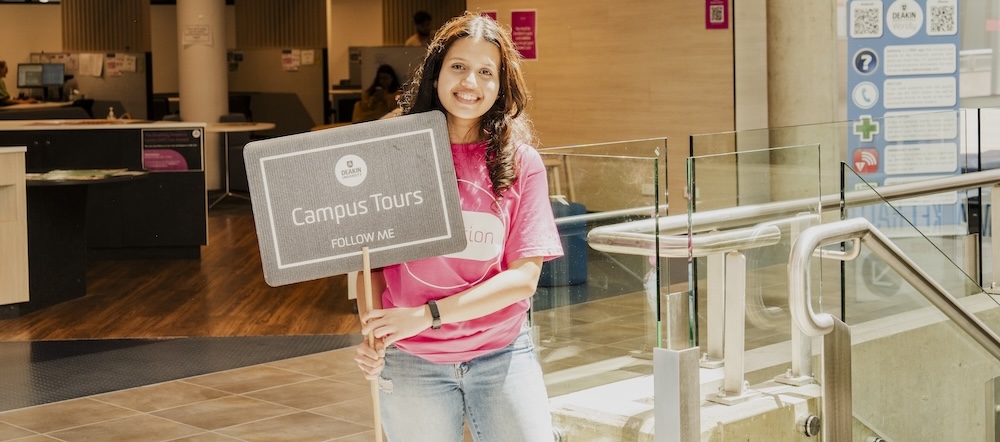 Student experience ambassador Student experience ambassador holding a tours sign