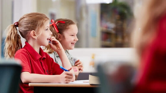 Two students sitting in a classroom run by a Deakin master of teaching primary teacher.