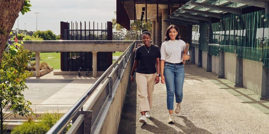 Two students walking and looking directly at the camera at the Geelong Waurn Ponds Campus.
