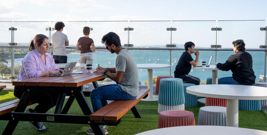 Deakin students sit outside at a table on the rooftop of Deakin Geelong Waterfront Campus.